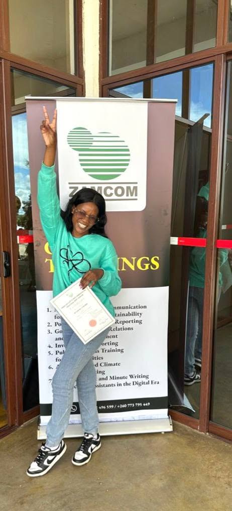 A graduate celebrating with her certificate outside the training venue